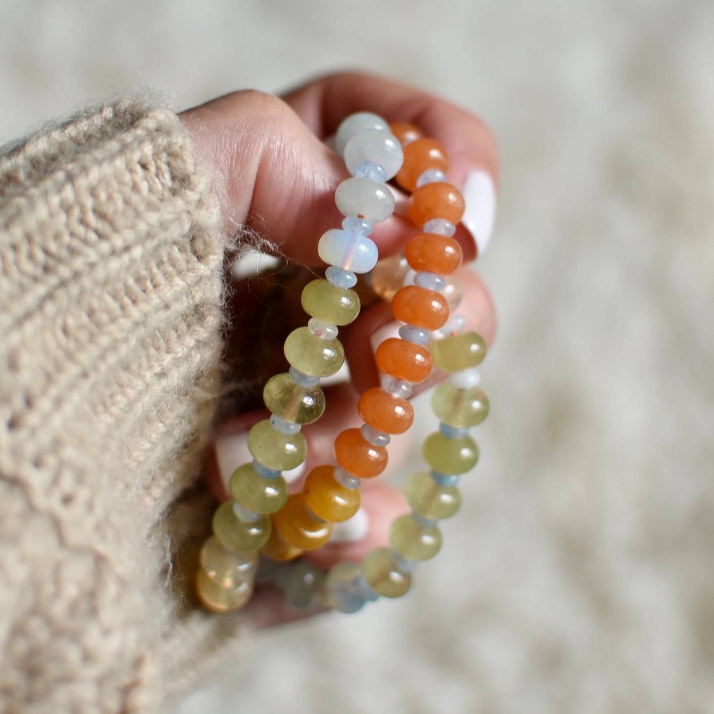 Hand holding two beaded necklace