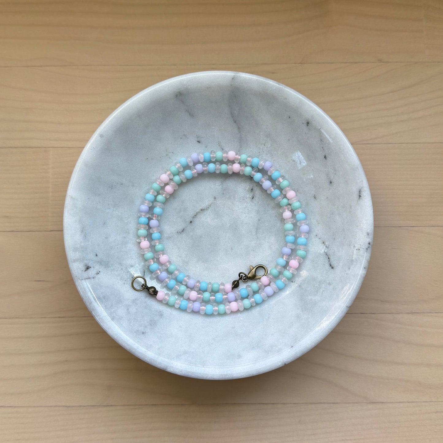Beaded bracelet on a marble dish with a wooden background