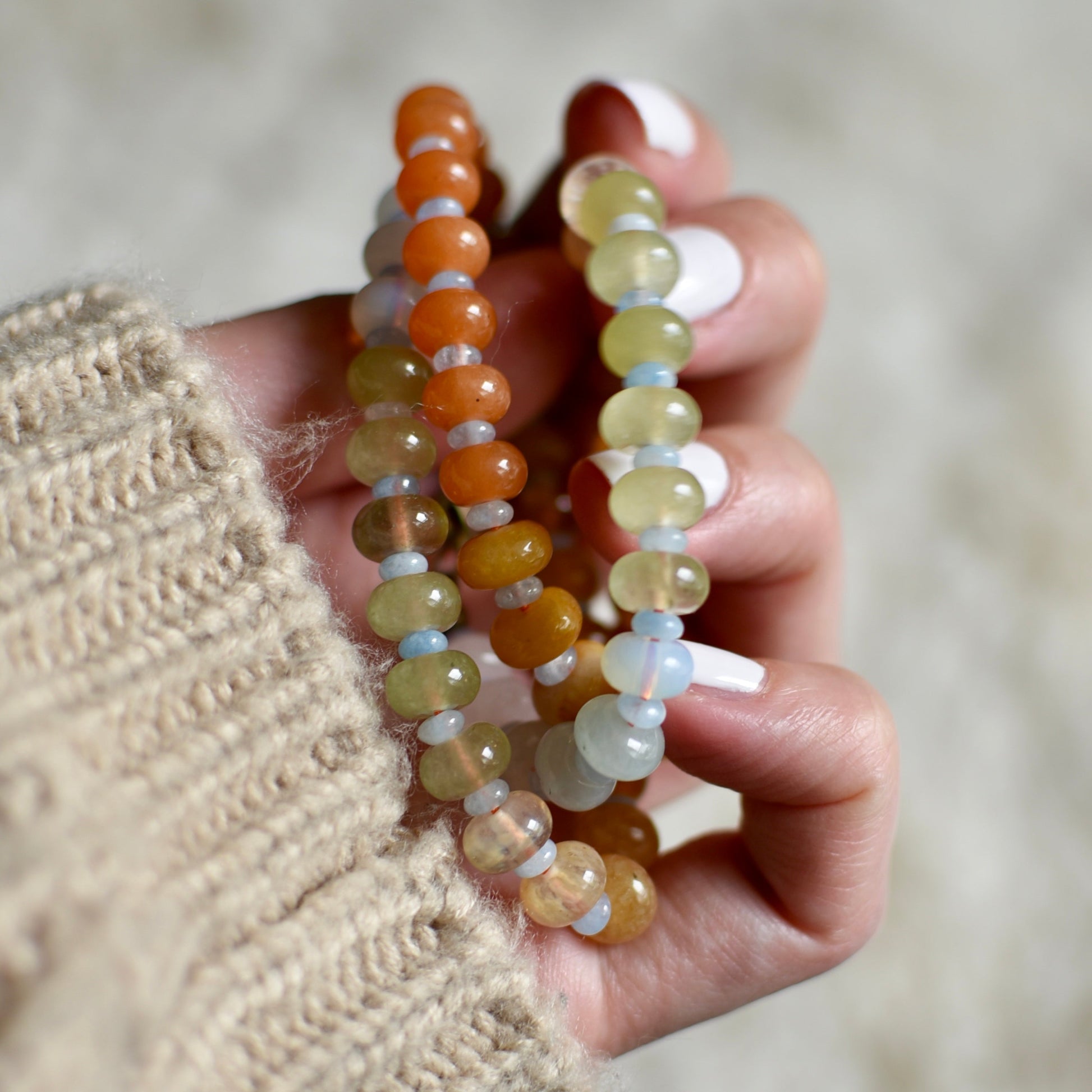 Hand holding two beaded necklace