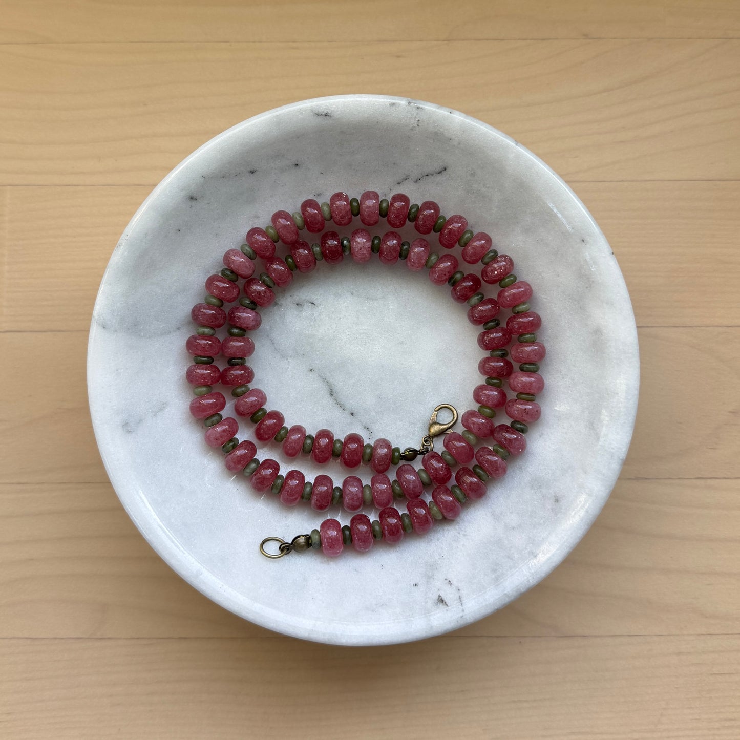 Beaded necklace on a marble dish with a wooden background