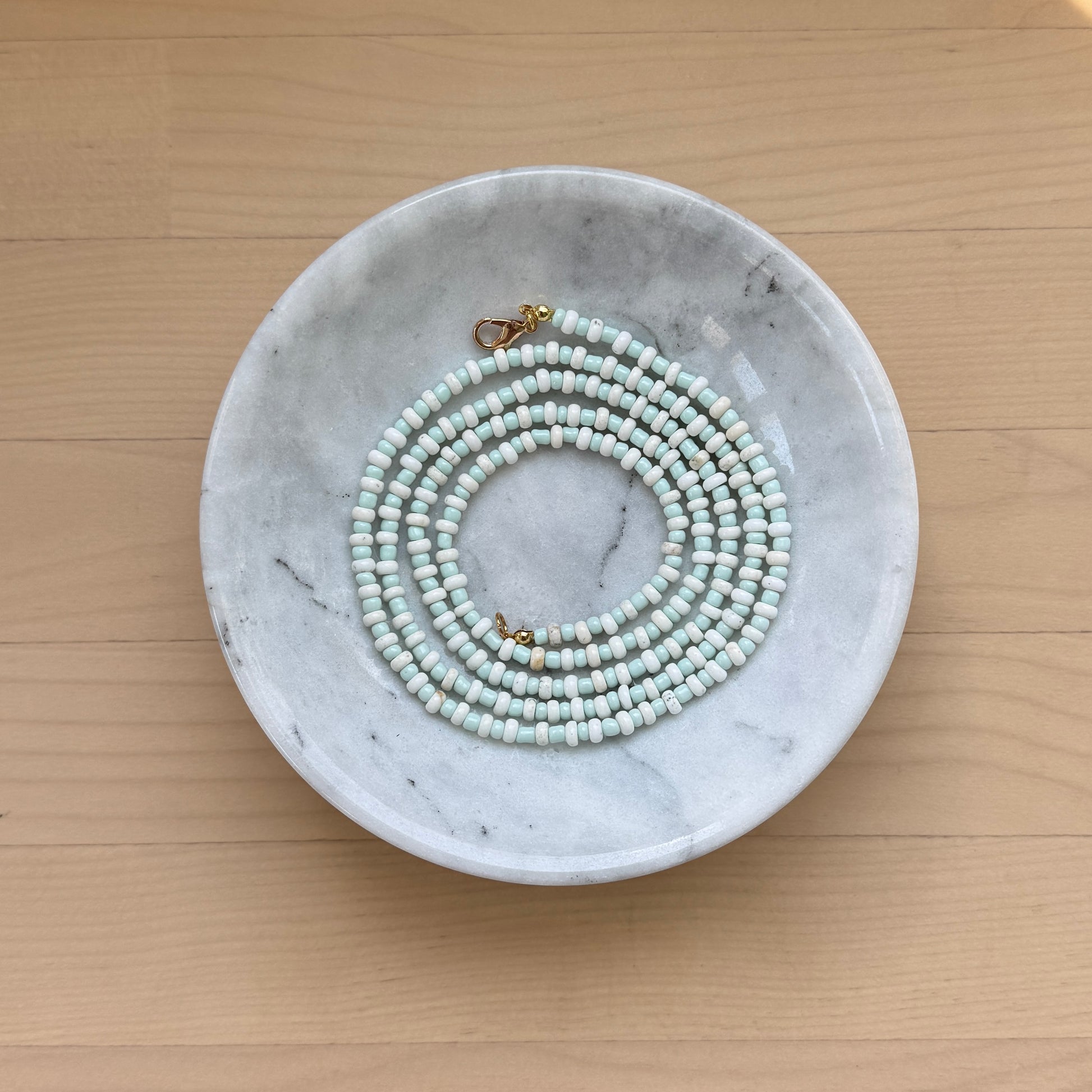 Marble dish with a necklace on a wooden surface